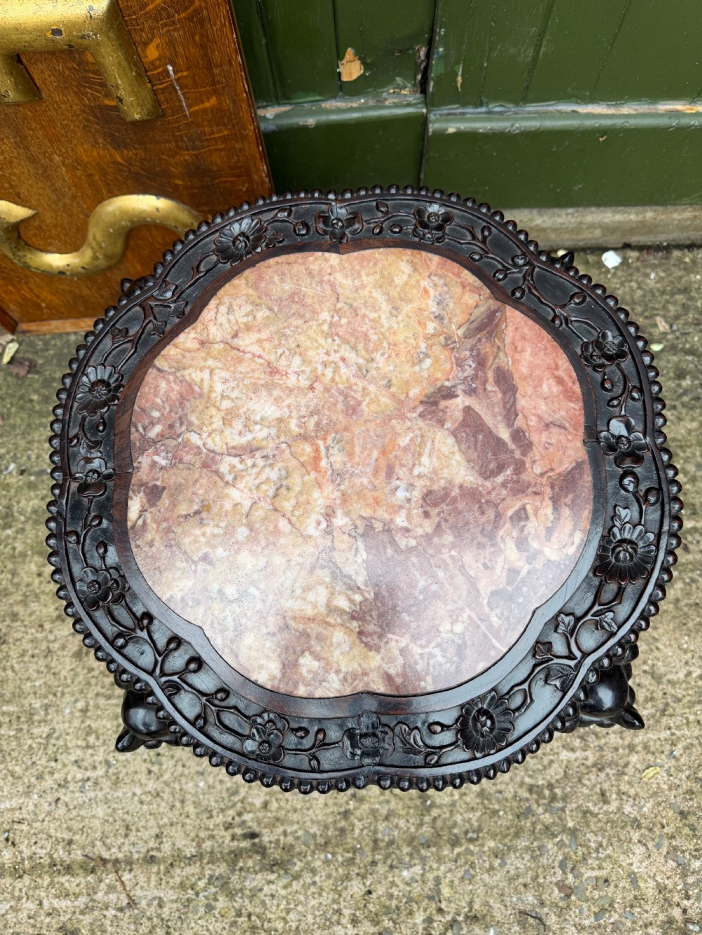 A late nineteenth-century Chinese carved dark hardwood jardiniere stand featuring a circular inset pink variegated marble top, intricate pierced floral aprons, and carved cabriole legs. View XII