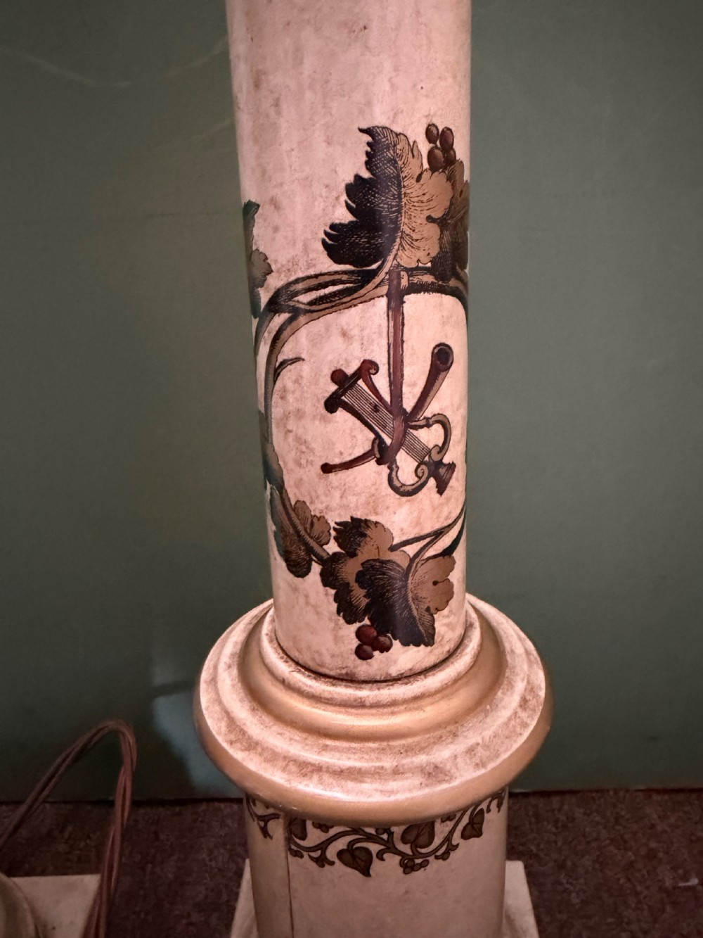 A pair of early twentieth-century French cream tole-peinte column table lamps decorated with hand-painted vine leaves, musical motifs, and gilt trim. View VI