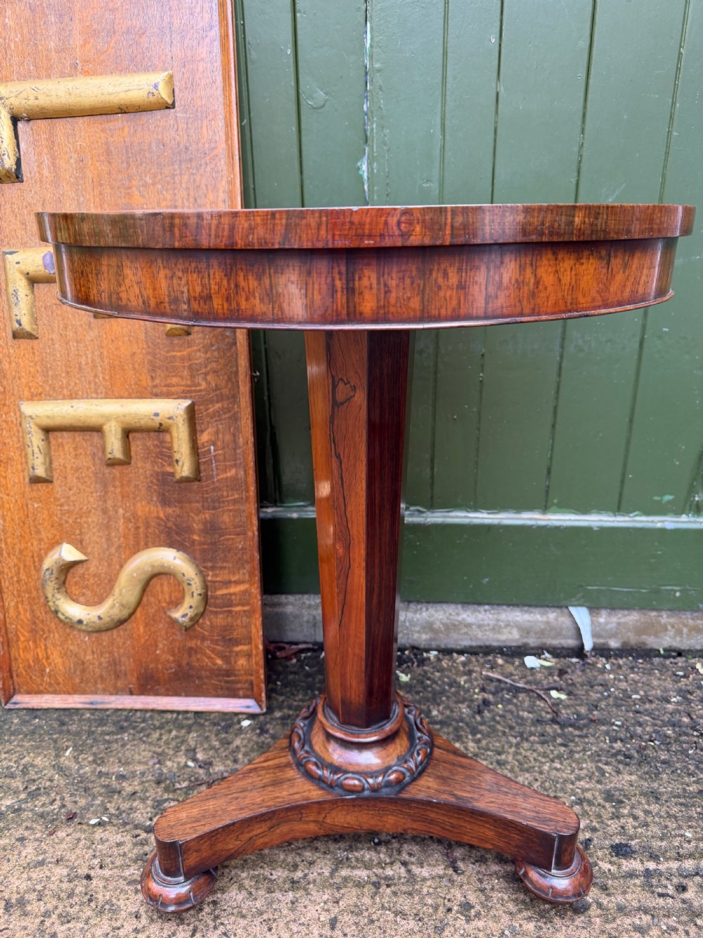 An early nineteenth-century circular rosewood occasional table featuring a deep apron, a faceted central pedestal, and a triform base with carved detail.