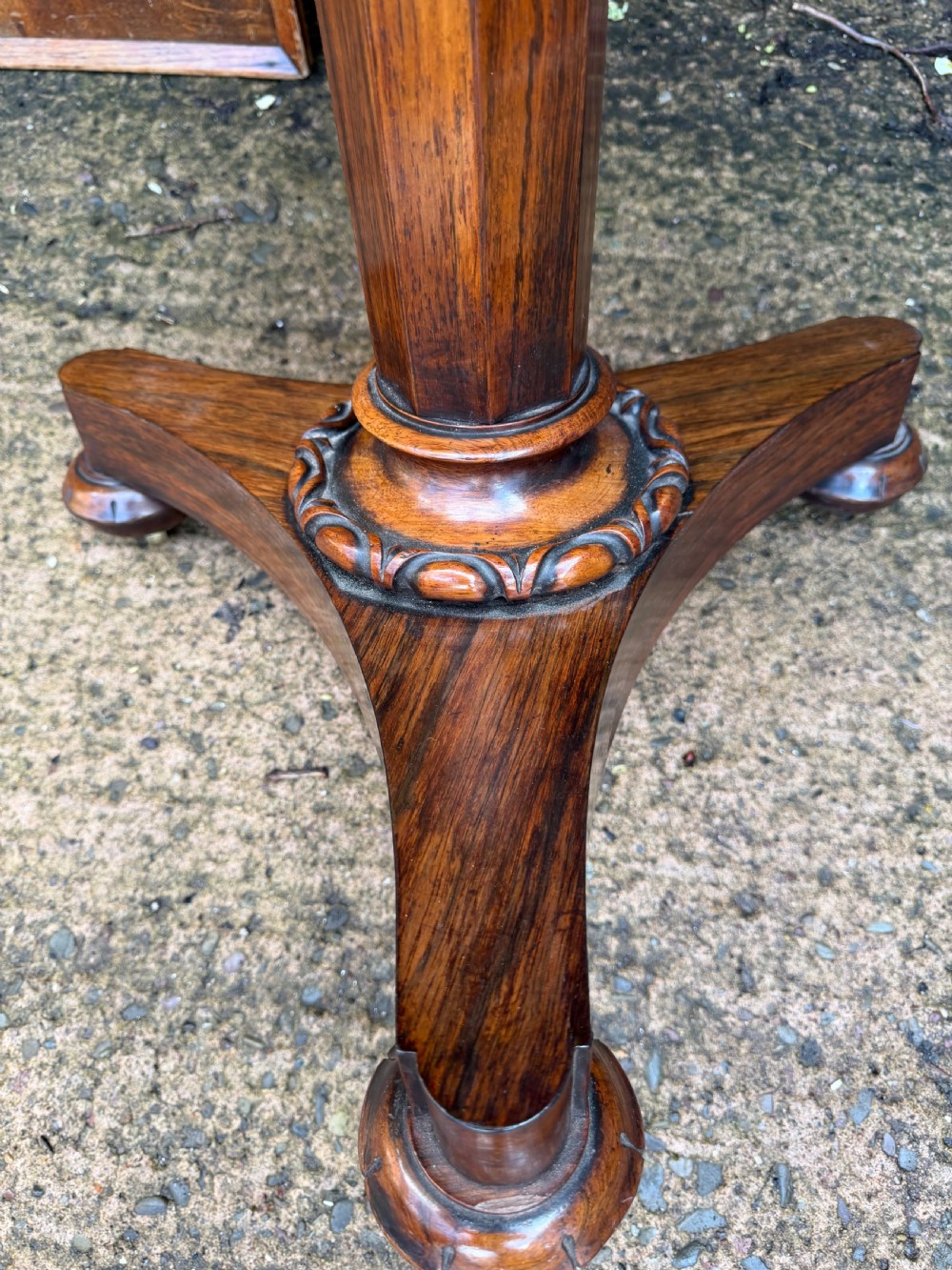 An early nineteenth-century circular rosewood occasional table featuring a deep apron, a faceted central pedestal, and a triform base with carved detail. View XI