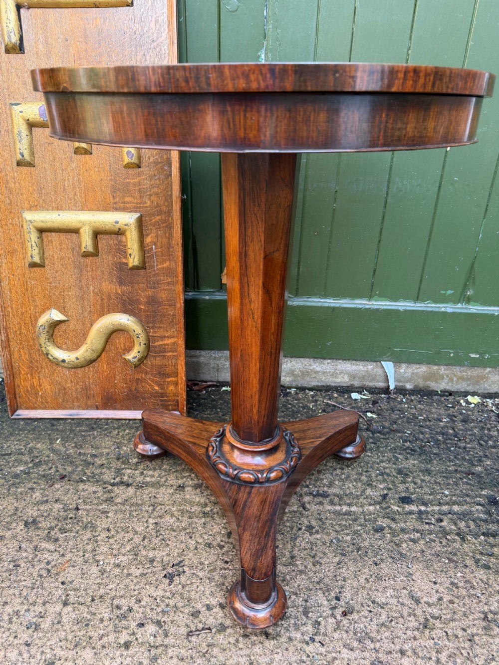 An early nineteenth-century circular rosewood occasional table featuring a deep apron, a faceted central pedestal, and a triform base with carved detail. View XIII