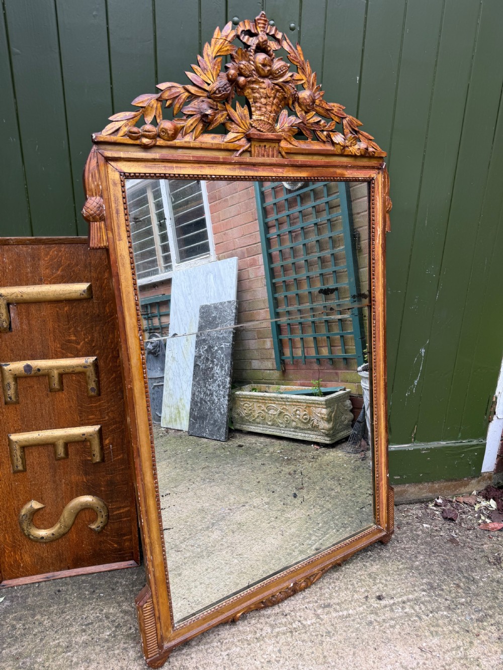 A large late eighteenth-century French giltwood wall mirror featuring a carved fruit basket pediment, floral foliage, and a rectangular beaded frame. View III
