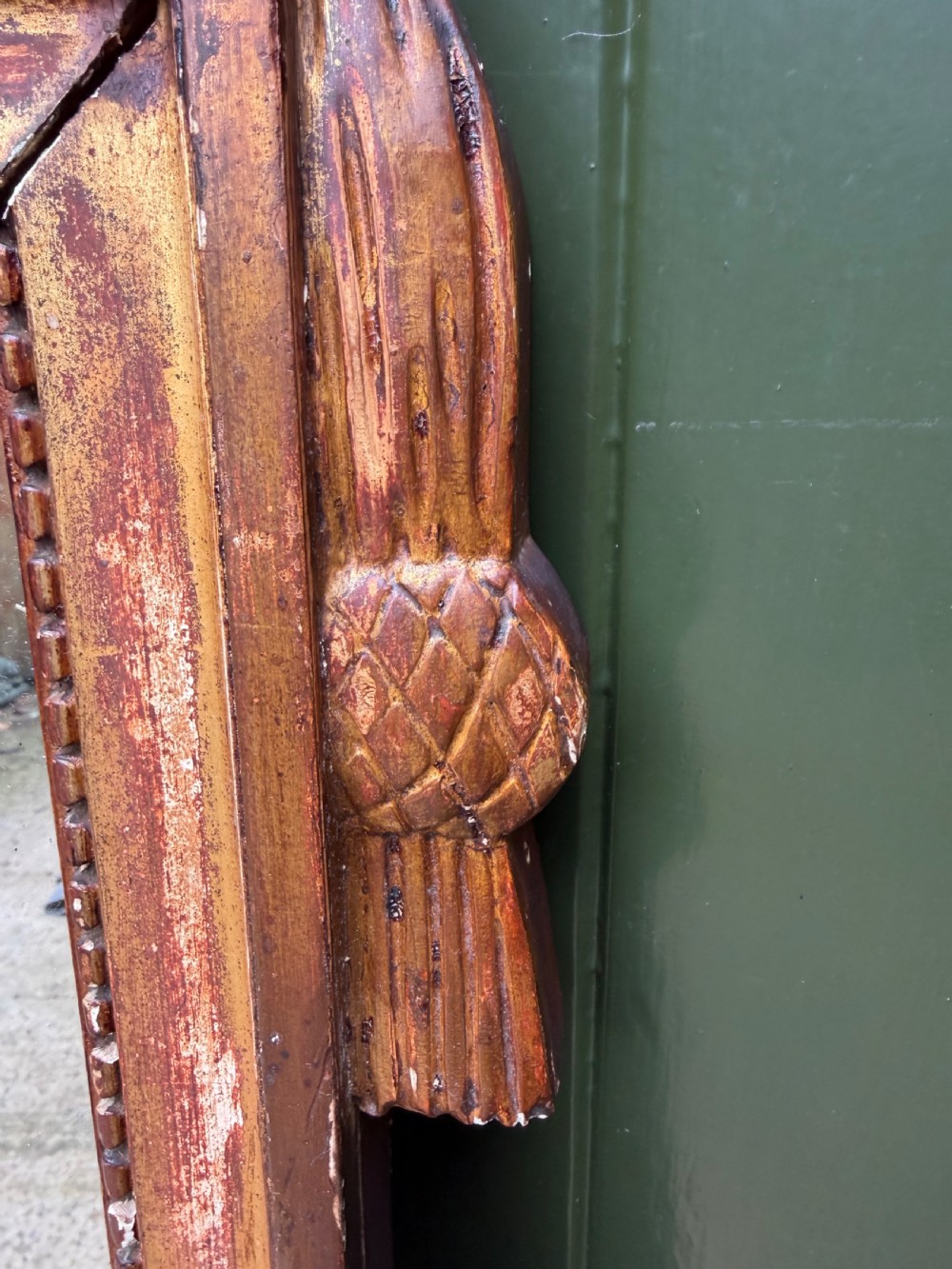 A large late eighteenth-century French giltwood wall mirror featuring a carved fruit basket pediment, floral foliage, and a rectangular beaded frame. View VII