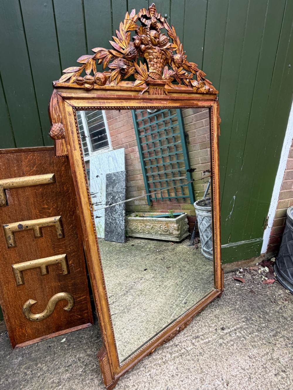 A large late eighteenth-century French giltwood wall mirror featuring a carved fruit basket pediment, floral foliage, and a rectangular beaded frame. View IX
