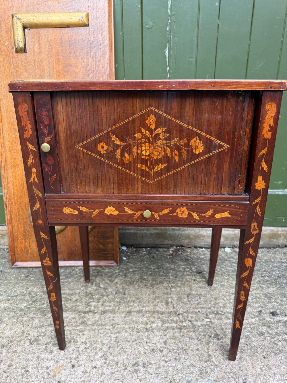 A Dutch mahogany bedside cupboard featuring floral marquetry inlays, a tambour slatted door, a single lower drawer with brass handles, and square tapered legs. View XII