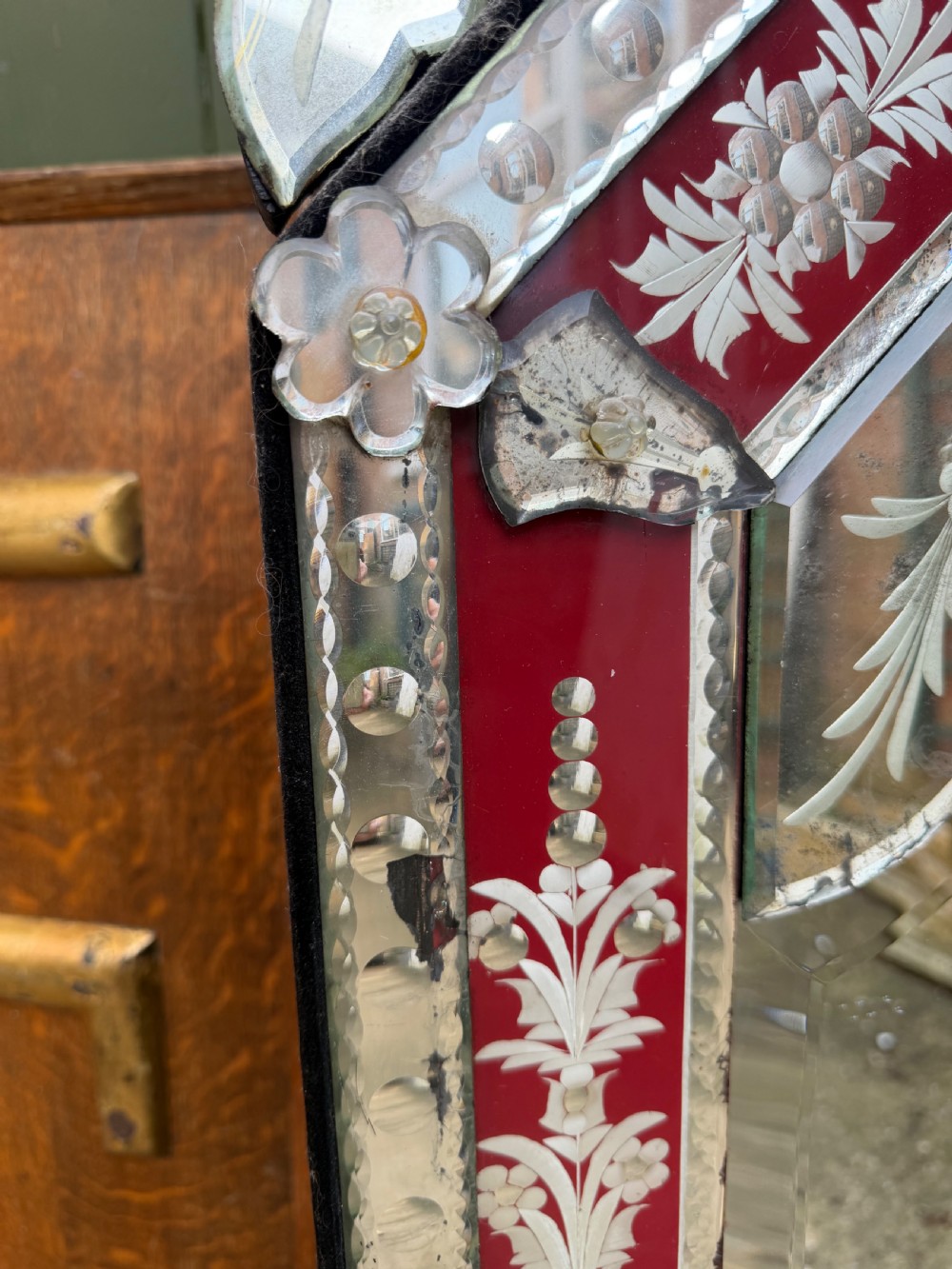 An antique Venetian wall mirror featuring cut and etched glass borders with ruby red glass accents and a decorative pediment crest. View II