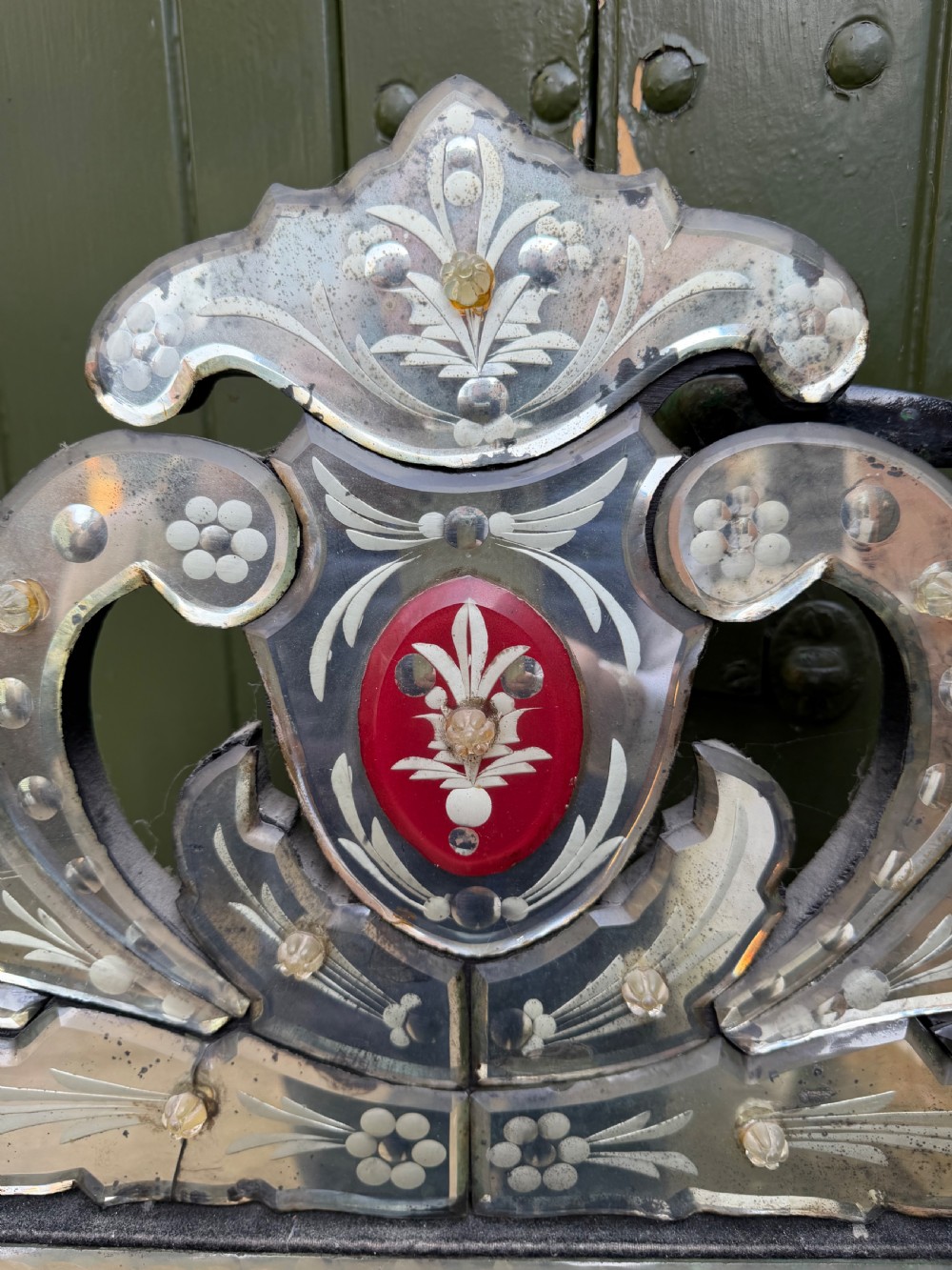 An antique Venetian wall mirror featuring cut and etched glass borders with ruby red glass accents and a decorative pediment crest. View III
