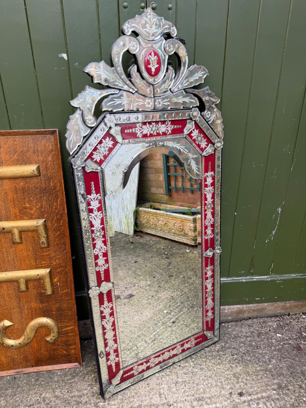 An antique Venetian wall mirror featuring cut and etched glass borders with ruby red glass accents and a decorative pediment crest. View V