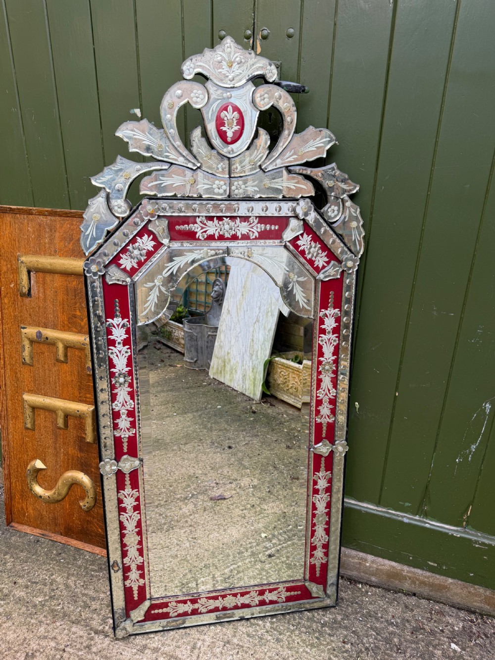 An antique Venetian wall mirror featuring cut and etched glass borders with ruby red glass accents and a decorative pediment crest. View VII