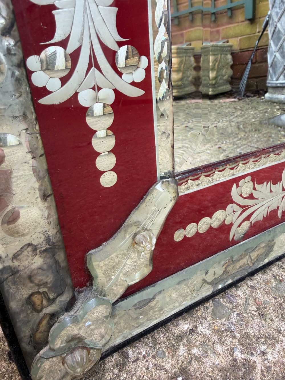 An antique Venetian wall mirror featuring cut and etched glass borders with ruby red glass accents and a decorative pediment crest. View XII