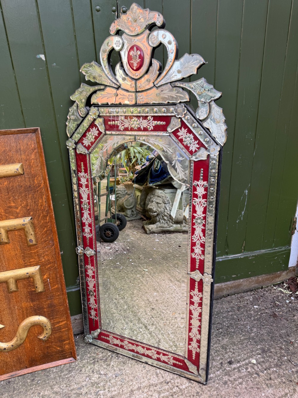 An antique Venetian wall mirror featuring cut and etched glass borders with ruby red glass accents and a decorative pediment crest. View XV