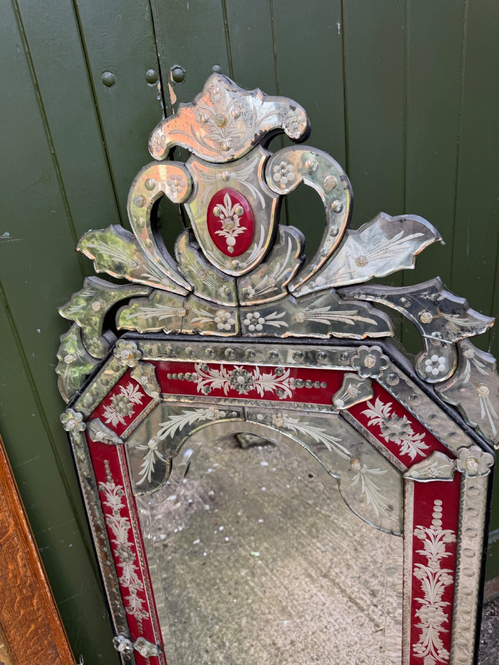 An antique Venetian wall mirror featuring cut and etched glass borders with ruby red glass accents and a decorative pediment crest. View XVI