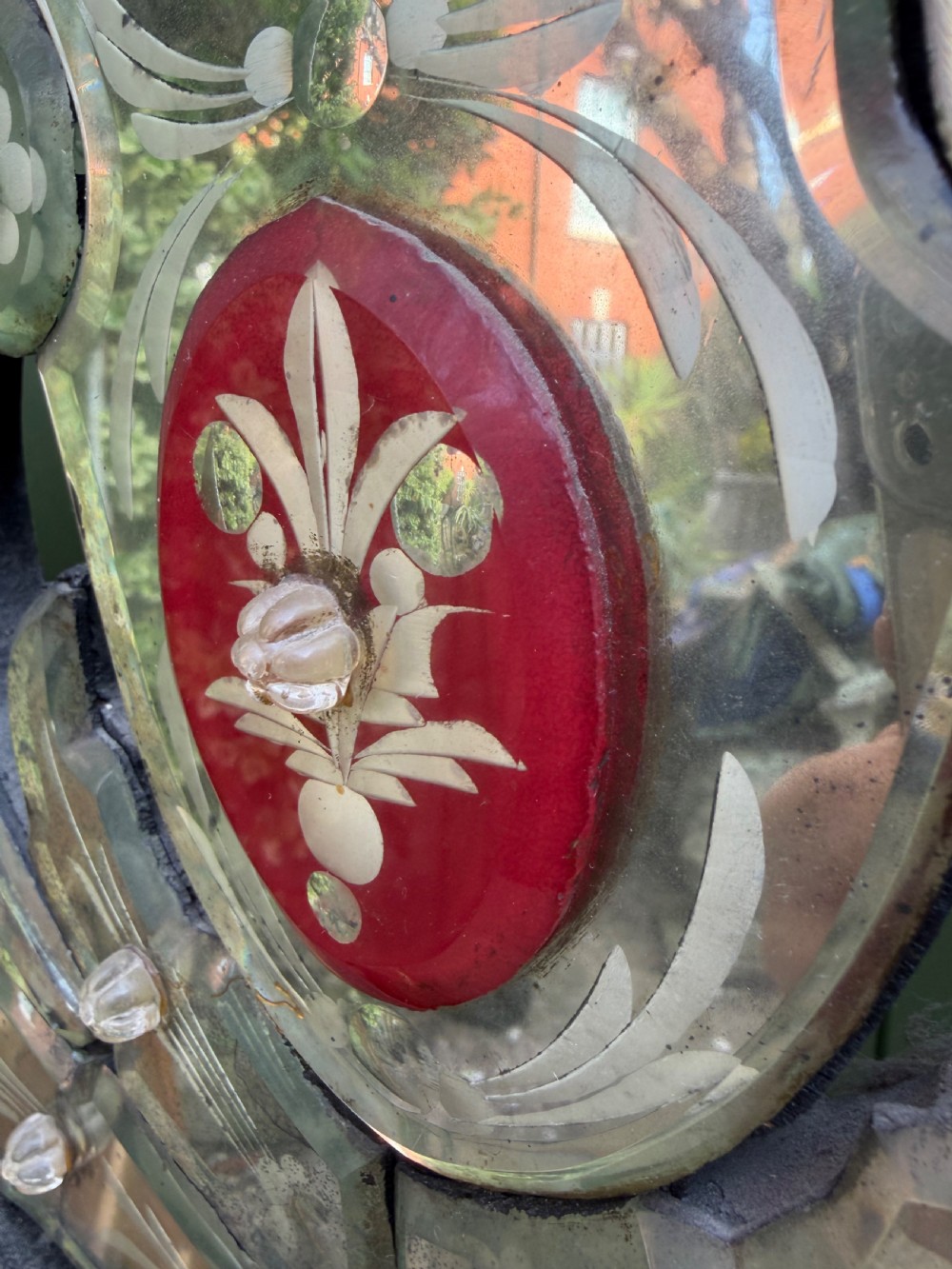 An antique Venetian wall mirror featuring cut and etched glass borders with ruby red glass accents and a decorative pediment crest. View XVII