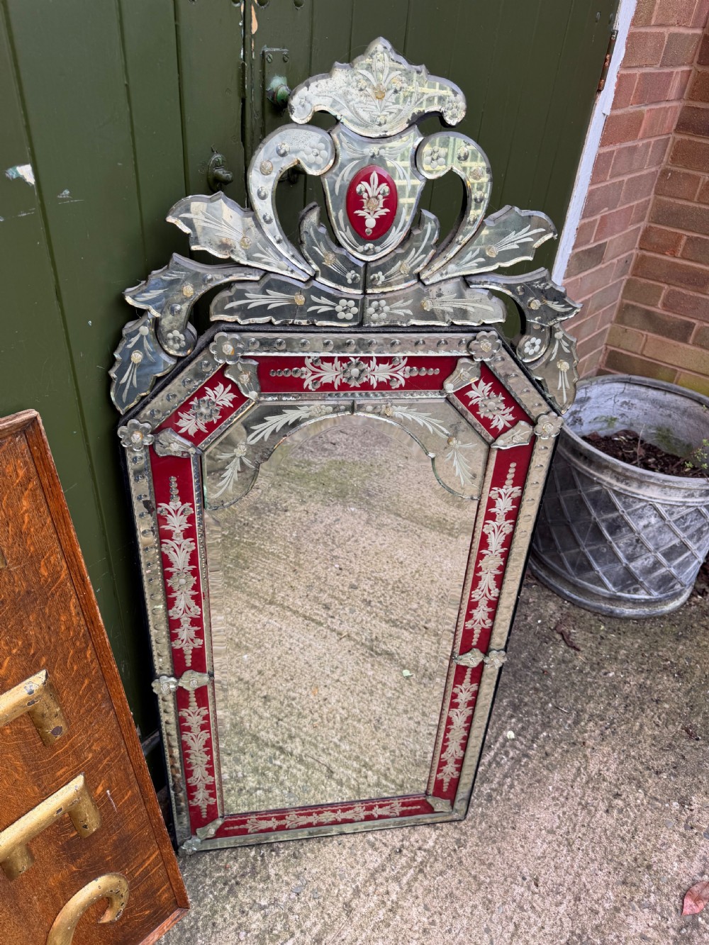 An antique Venetian wall mirror featuring cut and etched glass borders with ruby red glass accents and a decorative pediment crest. View XVIII