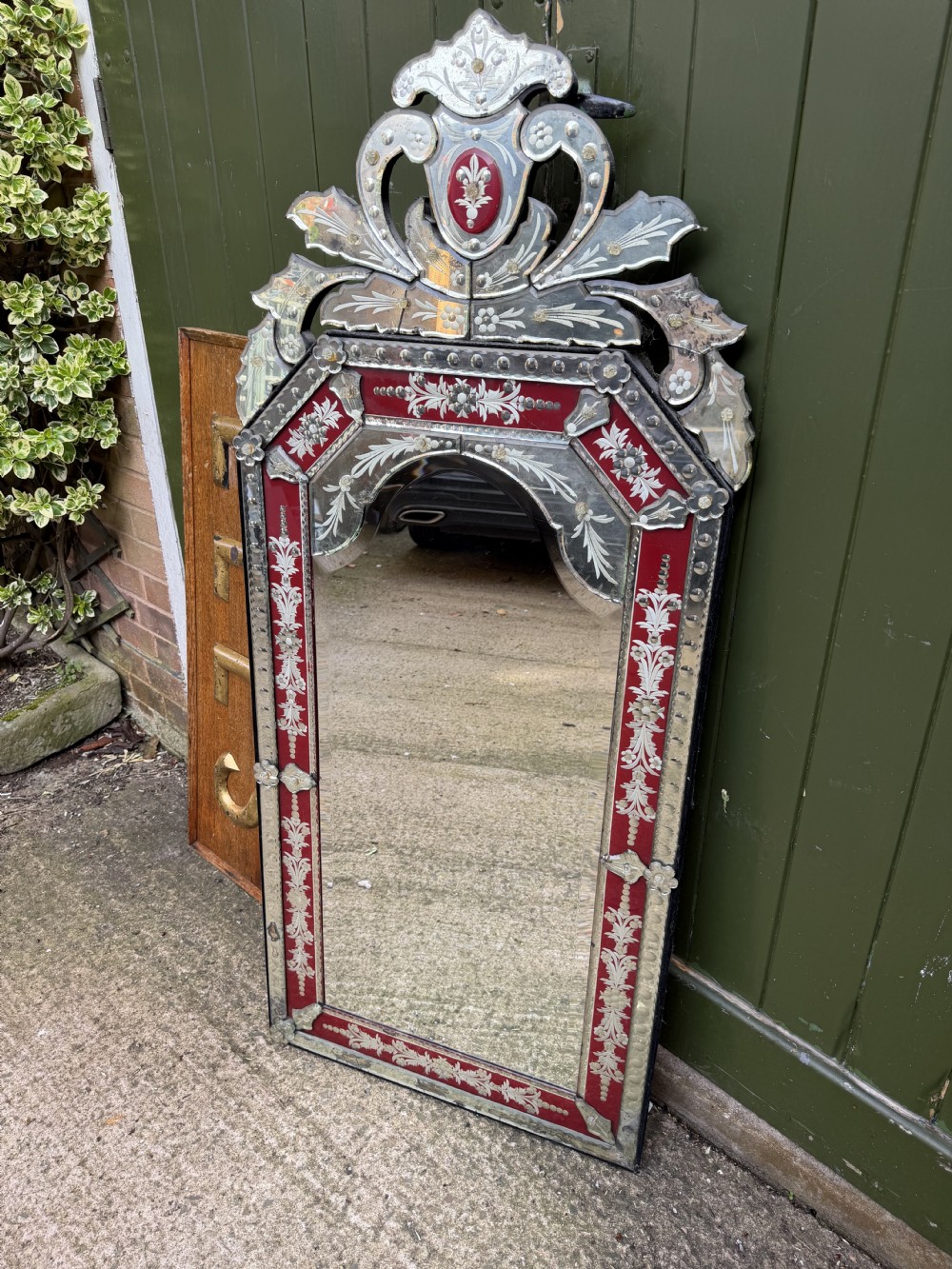An antique Venetian wall mirror featuring cut and etched glass borders with ruby red glass accents and a decorative pediment crest. View XXI
