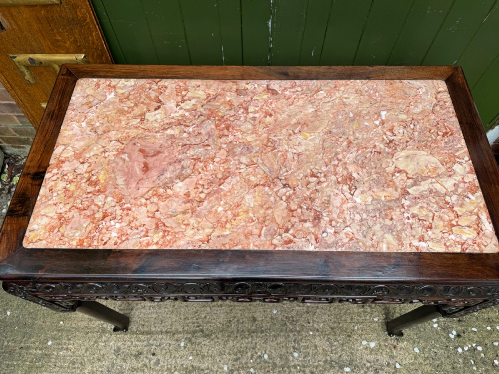 Late 19th-century Chinese Qing Dynasty dark hardwood centre table featuring an inset pink rouge marble rectangular top and intricately carved fretwork aprons. View II