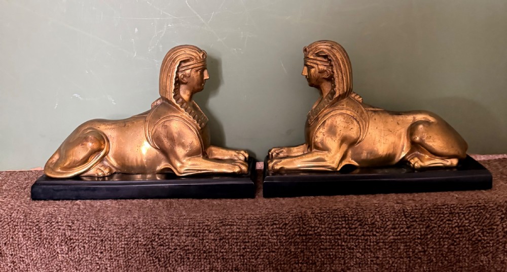 A pair of early nineteenth-century gilded bronze recumbent sphinxes resting on rectangular dark patinated bronze plinth bases. View V