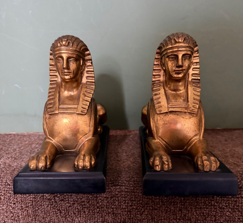 A pair of early nineteenth-century gilded bronze recumbent sphinxes resting on rectangular dark patinated bronze plinth bases. View VIII