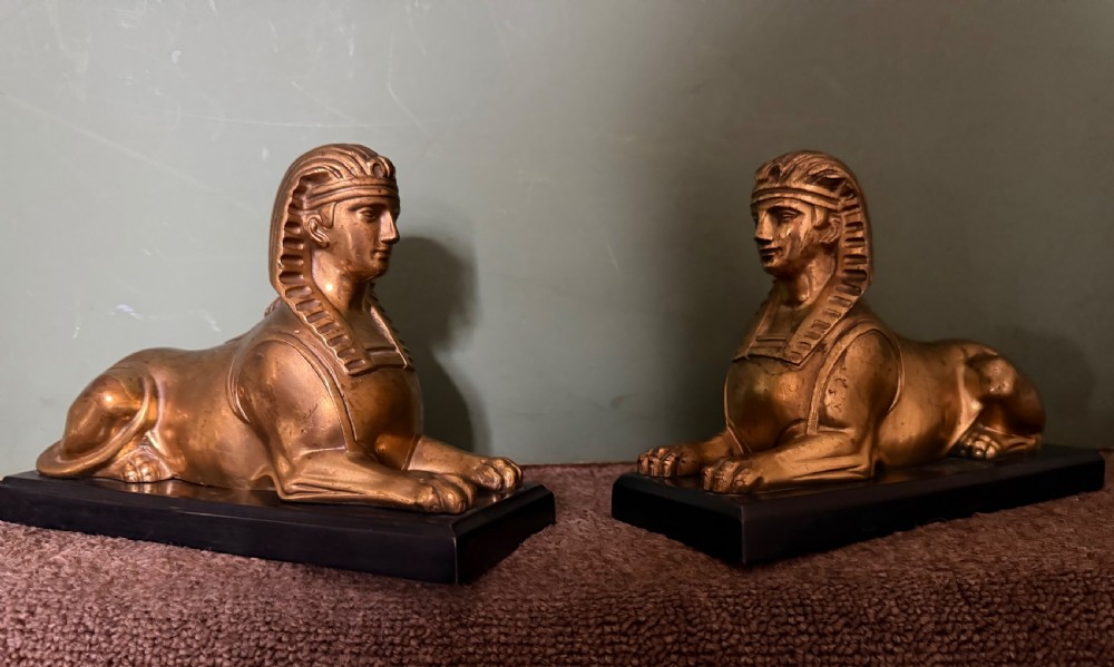 A pair of early nineteenth-century gilded bronze recumbent sphinxes resting on rectangular dark patinated bronze plinth bases. View XX