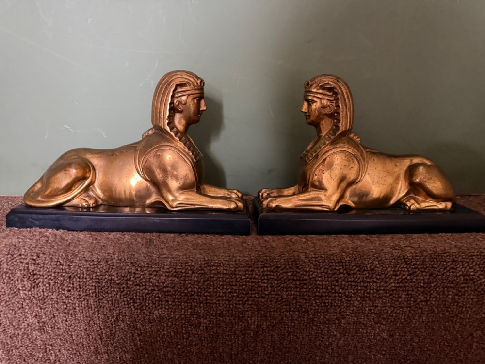 A pair of early nineteenth-century gilded bronze recumbent sphinxes resting on rectangular dark patinated bronze plinth bases. View XXI