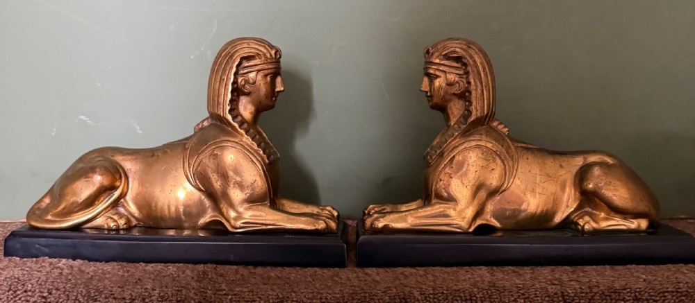 A pair of early nineteenth-century gilded bronze recumbent sphinxes resting on rectangular dark patinated bronze plinth bases. View XXII