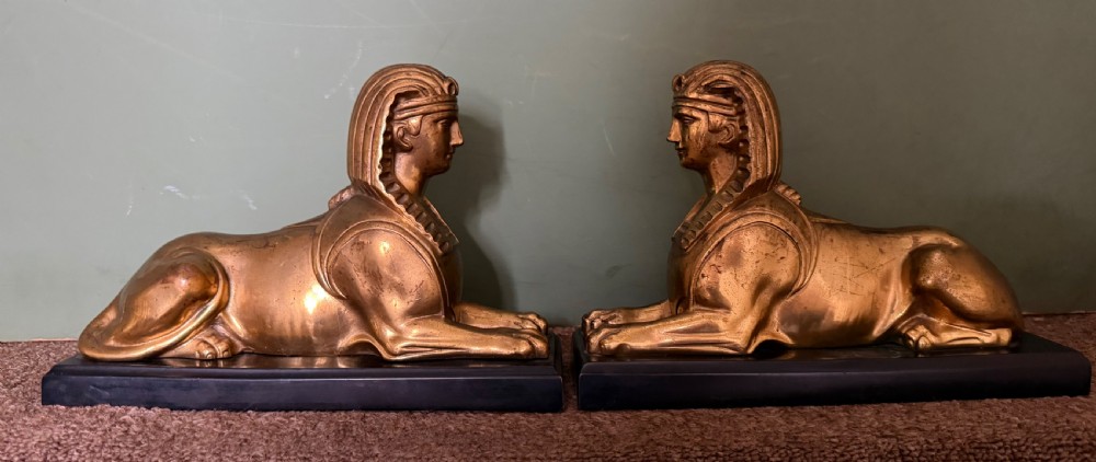 A pair of early nineteenth-century gilded bronze recumbent sphinxes resting on rectangular dark patinated bronze plinth bases. View XXIII