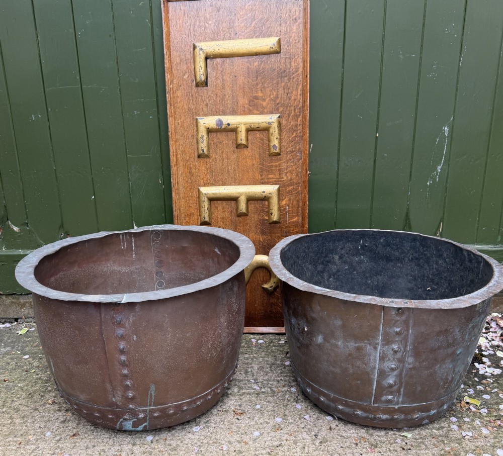 A matched pair of 19th-century copper wash tubs with riveted seams, wide rolled rims, and natural verdigris oxidisation.