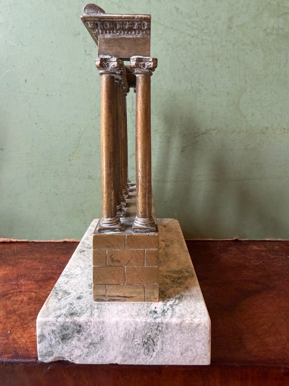 A set of three late 19th-century miniature polished bronze models representing ancient Roman temple ruins mounted on green marble bases. View II