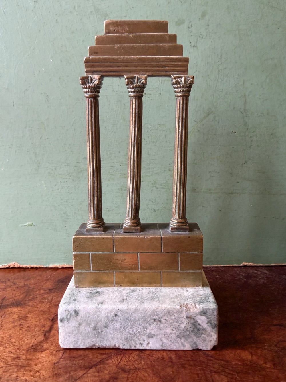A set of three late 19th-century miniature polished bronze models representing ancient Roman temple ruins mounted on green marble bases. View V