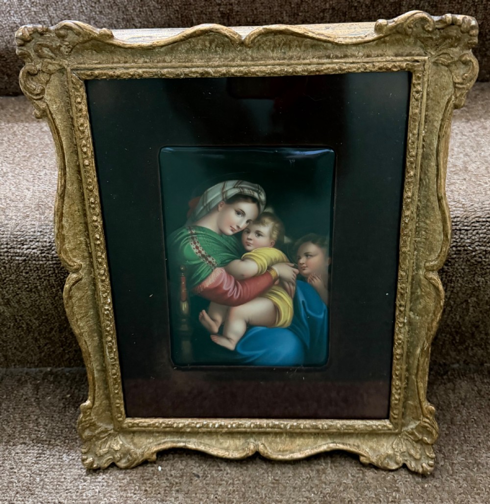 A late nineteenth-century hand-painted rectangular porcelain plaque depicting the Madonna and Child set within a velvet mount and an ornate swept gilt frame.