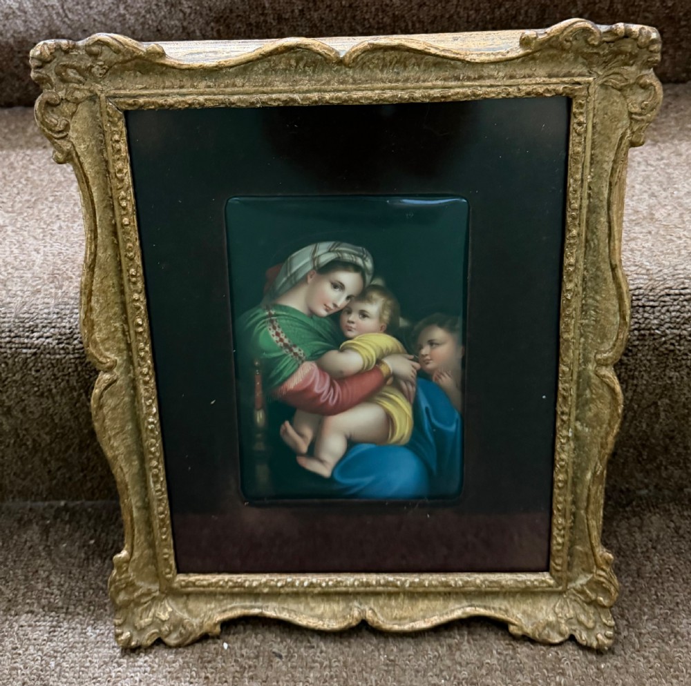 A late nineteenth-century hand-painted rectangular porcelain plaque depicting the Madonna and Child set within a velvet mount and an ornate swept gilt frame. View V