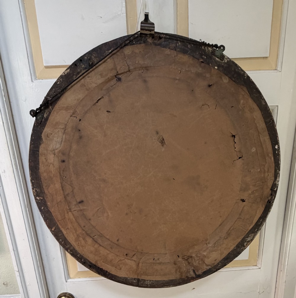 An early 19th-century Regency circular giltwood convex wall mirror featuring carved shell motifs, an ebonised reeded inner slip, and foxed mirror glass. View XII