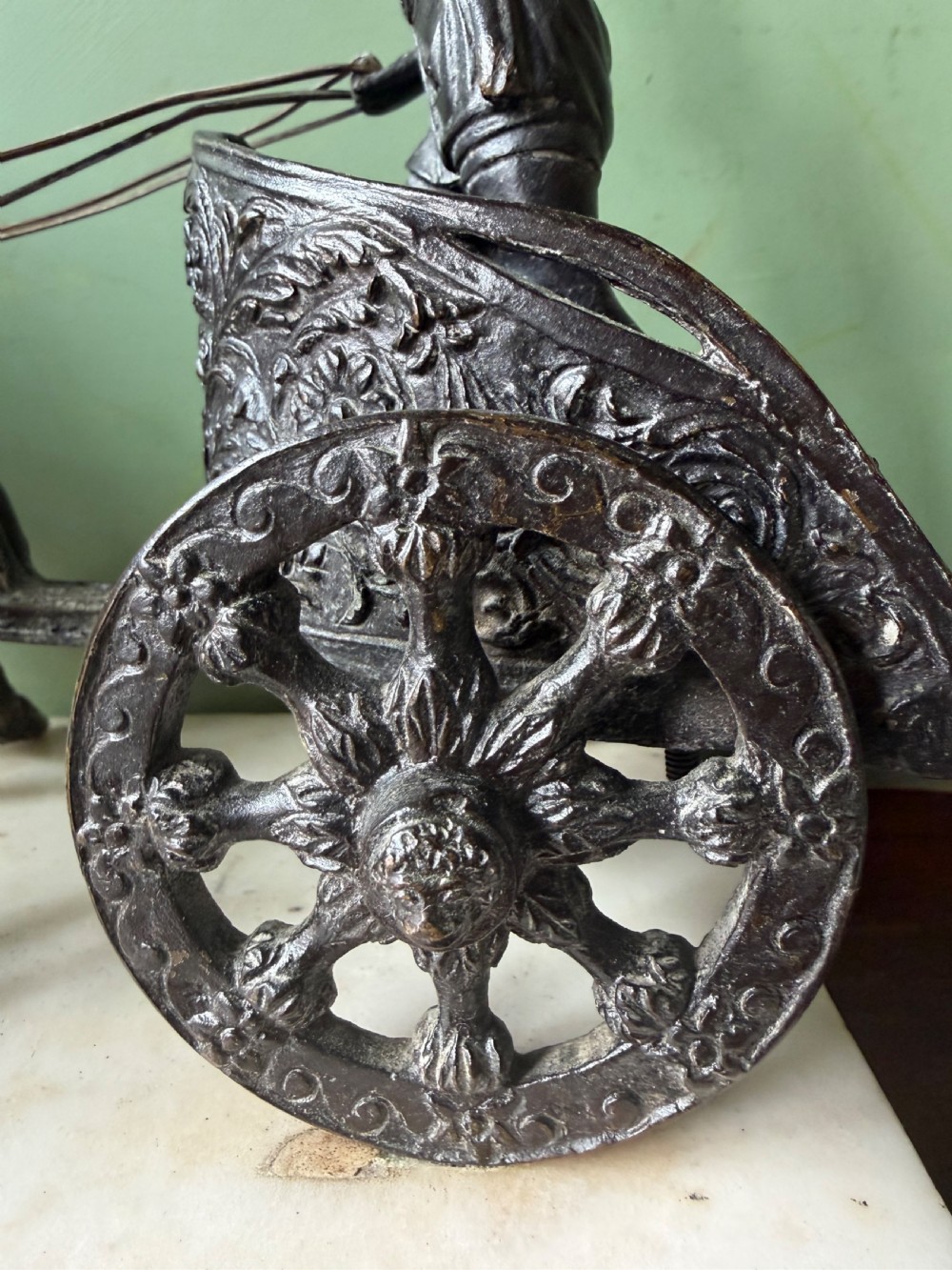 A mid-19th-century dark bronze sculpture depicting a Roman charioteer driving two rearing horses, mounted on a rectangular white marble plinth. View IV