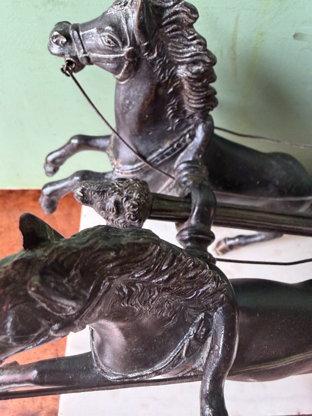 A mid-19th-century dark bronze sculpture depicting a Roman charioteer driving two rearing horses, mounted on a rectangular white marble plinth. View X