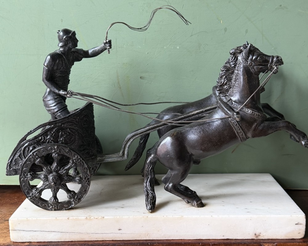 A mid-19th-century dark bronze sculpture depicting a Roman charioteer driving two rearing horses, mounted on a rectangular white marble plinth. View XV