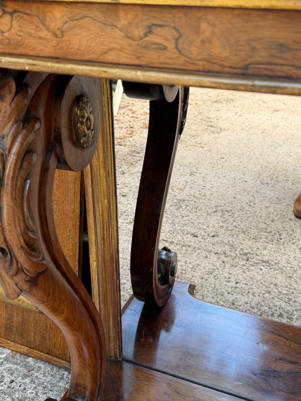 A Regency rosewood console table featuring a figured marble top, carved scroll legs with parcel-gilt details, an inset mirror back, and a plinth base. View III