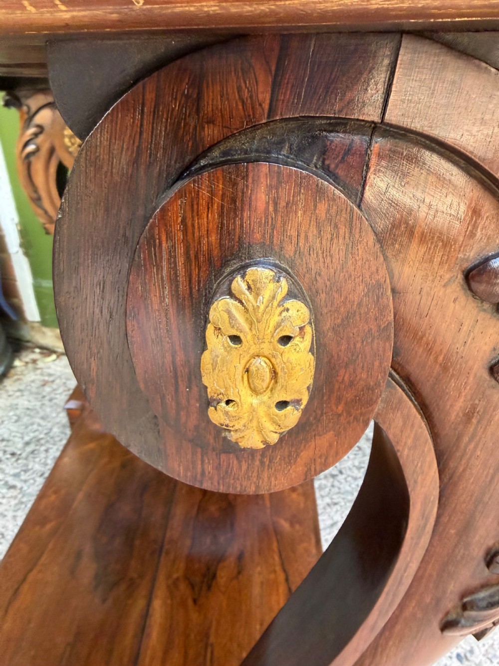 A Regency rosewood console table featuring a figured marble top, carved scroll legs with parcel-gilt details, an inset mirror back, and a plinth base. View VII