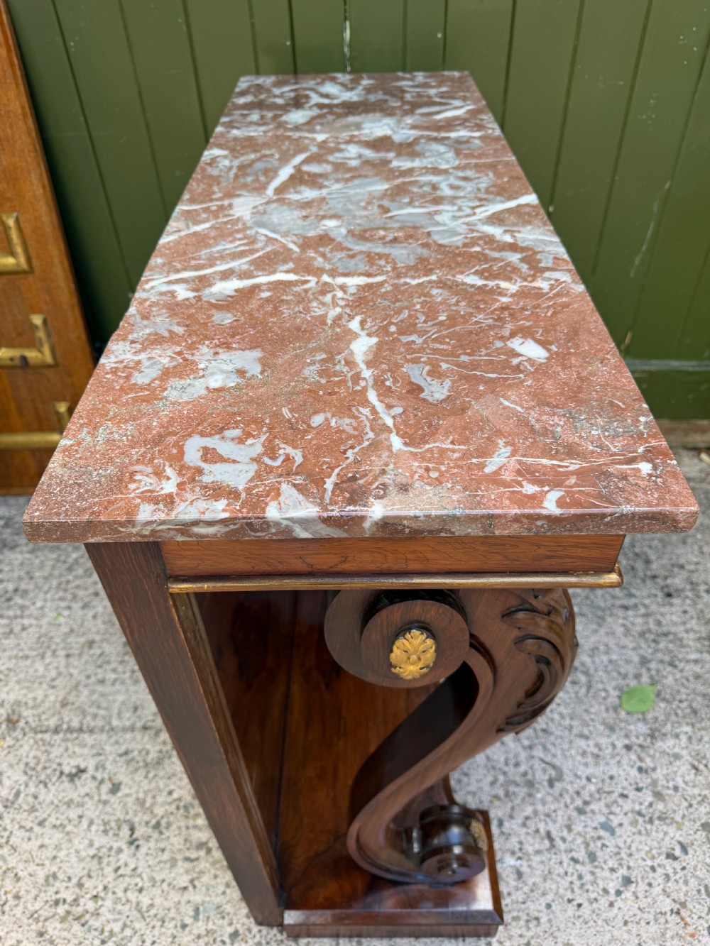A Regency rosewood console table featuring a figured marble top, carved scroll legs with parcel-gilt details, an inset mirror back, and a plinth base. View XI