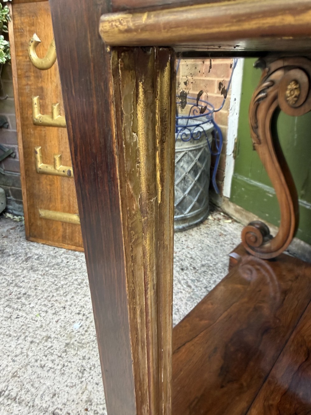 A Regency rosewood console table featuring a figured marble top, carved scroll legs with parcel-gilt details, an inset mirror back, and a plinth base. View XVIII