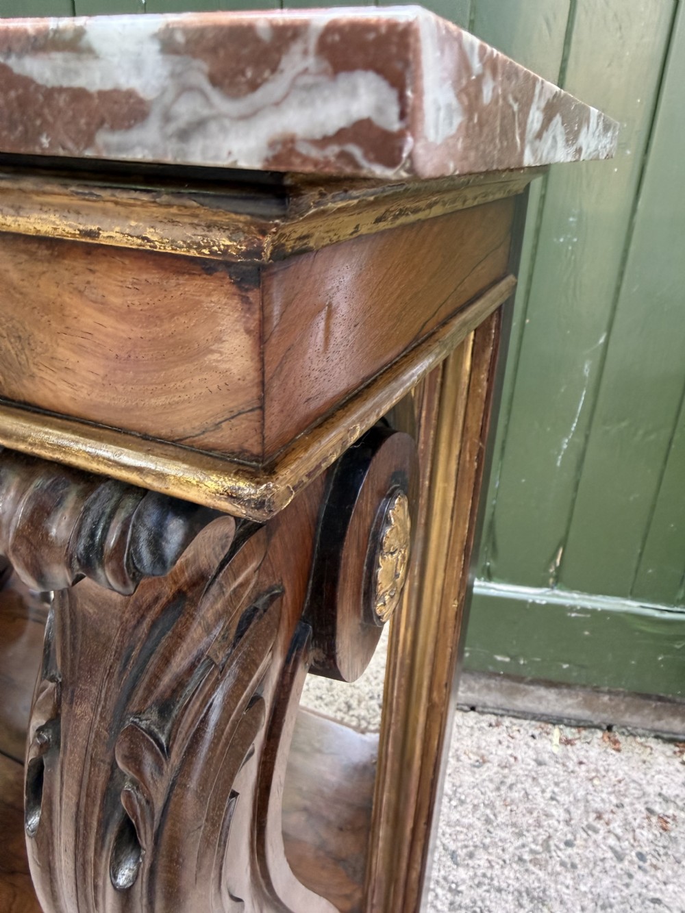 A Regency rosewood console table featuring a figured marble top, carved scroll legs with parcel-gilt details, an inset mirror back, and a plinth base. View XIX