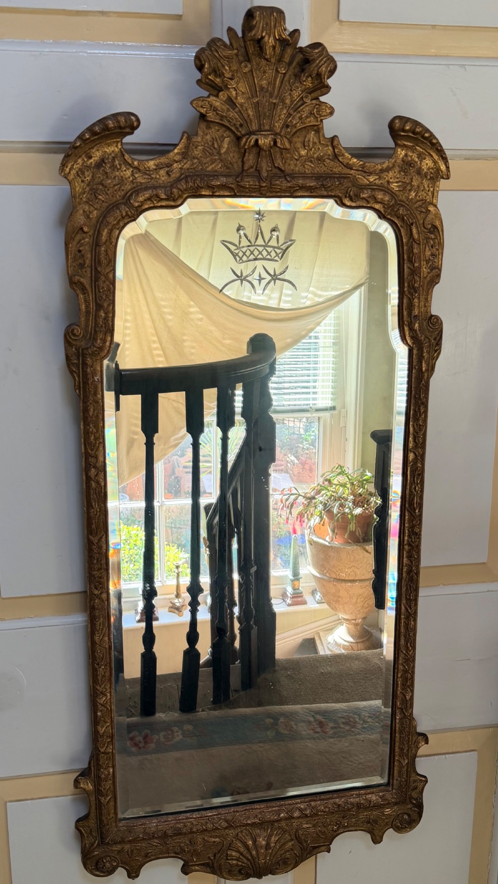 A tall, slender carved giltwood pier mirror featuring an ornate acanthus leaf cresting and an etched crest motif near the top of the glass plate. View II