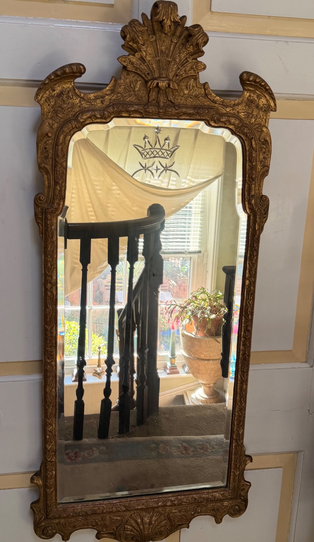 A tall, slender carved giltwood pier mirror featuring an ornate acanthus leaf cresting and an etched crest motif near the top of the glass plate. View IV