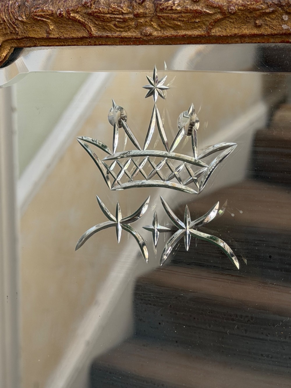 A tall, slender carved giltwood pier mirror featuring an ornate acanthus leaf cresting and an etched crest motif near the top of the glass plate. View VI