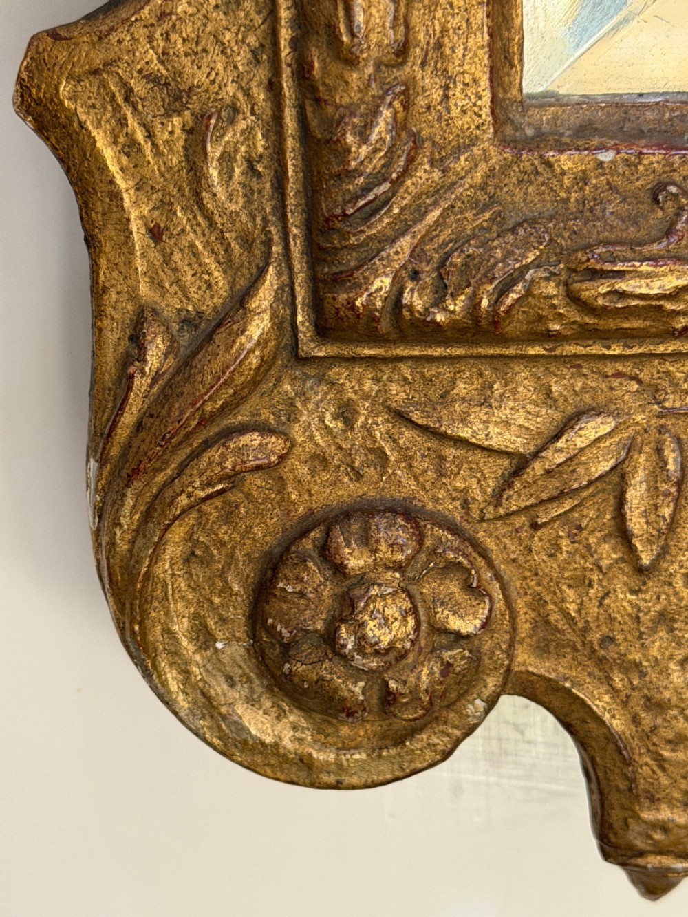 A tall, slender carved giltwood pier mirror featuring an ornate acanthus leaf cresting and an etched crest motif near the top of the glass plate. View VII