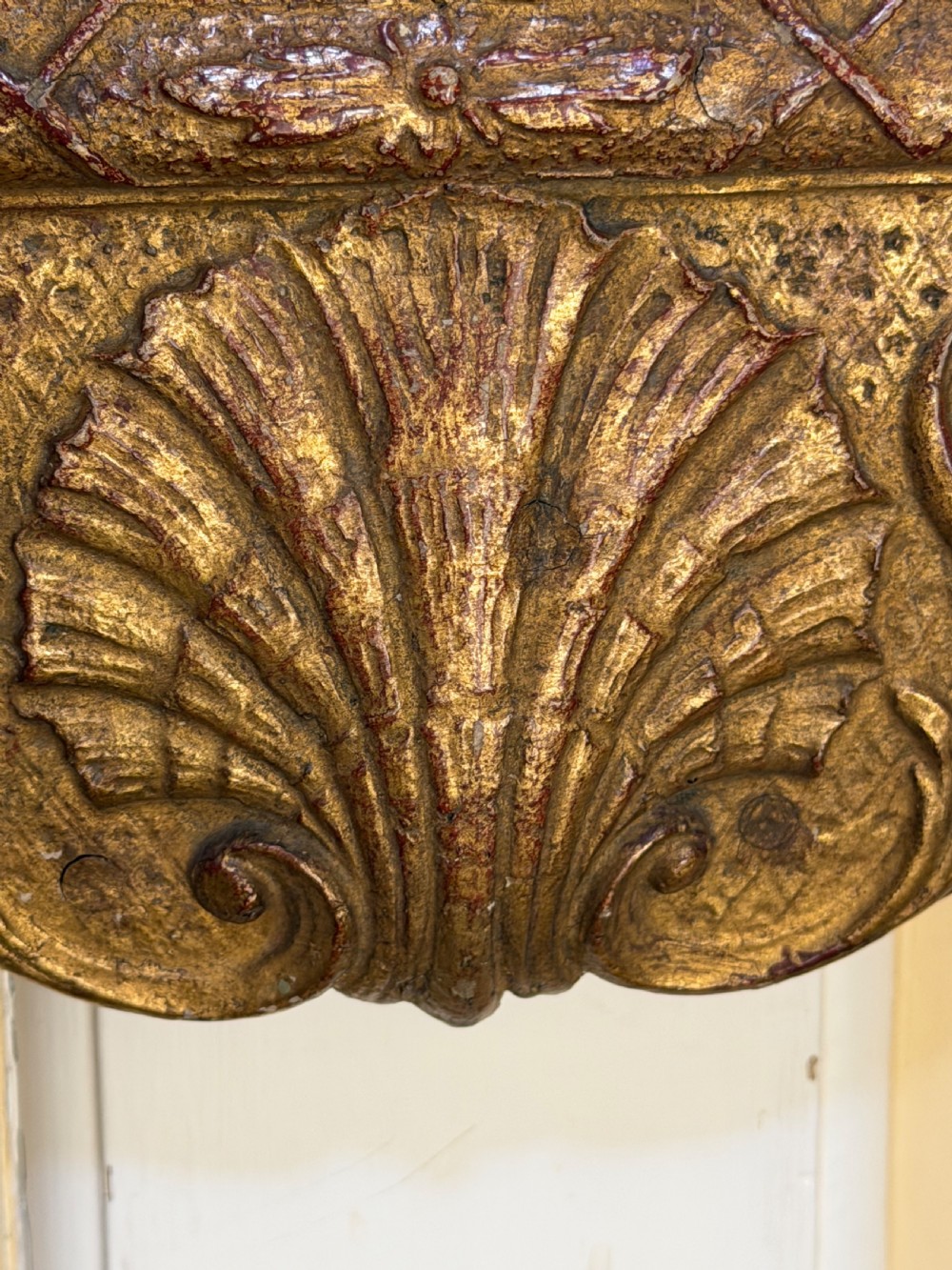A tall, slender carved giltwood pier mirror featuring an ornate acanthus leaf cresting and an etched crest motif near the top of the glass plate. View VIII