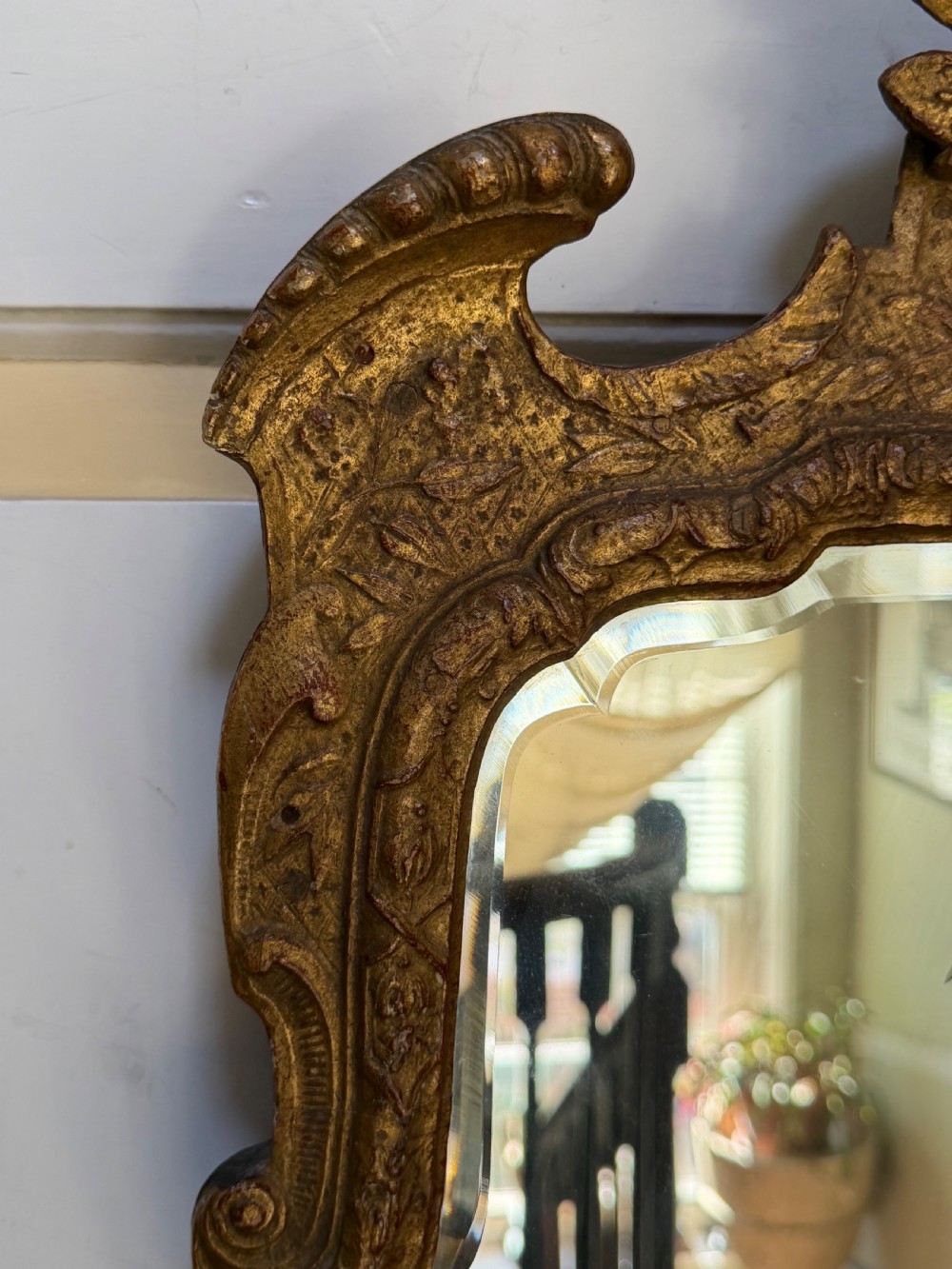 A tall, slender carved giltwood pier mirror featuring an ornate acanthus leaf cresting and an etched crest motif near the top of the glass plate. View XII