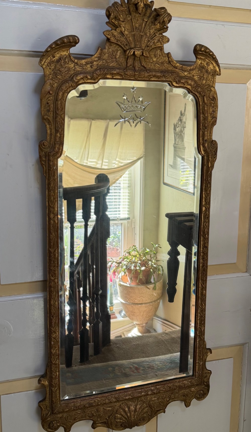 A tall, slender carved giltwood pier mirror featuring an ornate acanthus leaf cresting and an etched crest motif near the top of the glass plate. View XIV