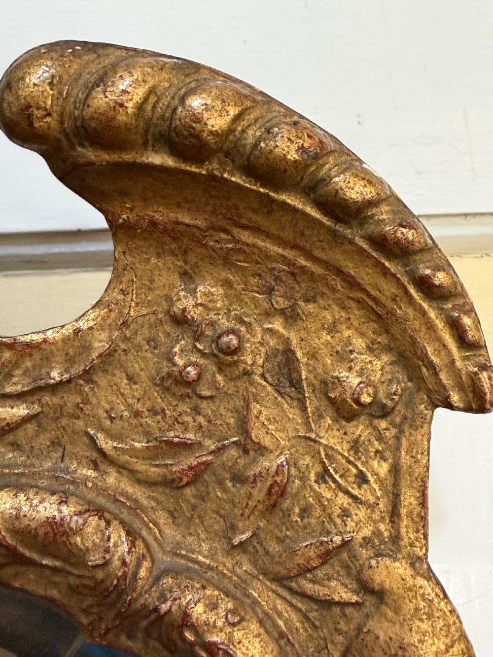 A tall, slender carved giltwood pier mirror featuring an ornate acanthus leaf cresting and an etched crest motif near the top of the glass plate. View XVI