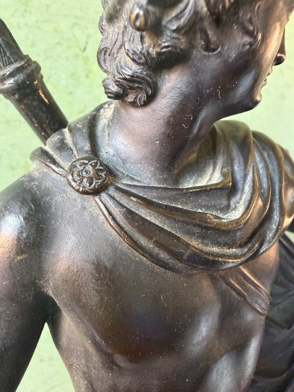 A dark patinated bronze figure depicting the classical god Apollo standing nude with drapery over his arm on a round base. View XVII