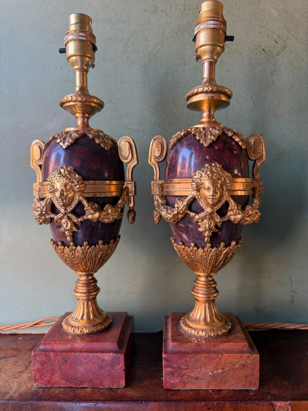 A pair of late nineteenth-century French rouge marble table lamps shaped as urns with gilt bronze mounts and square pedestal bases. View II